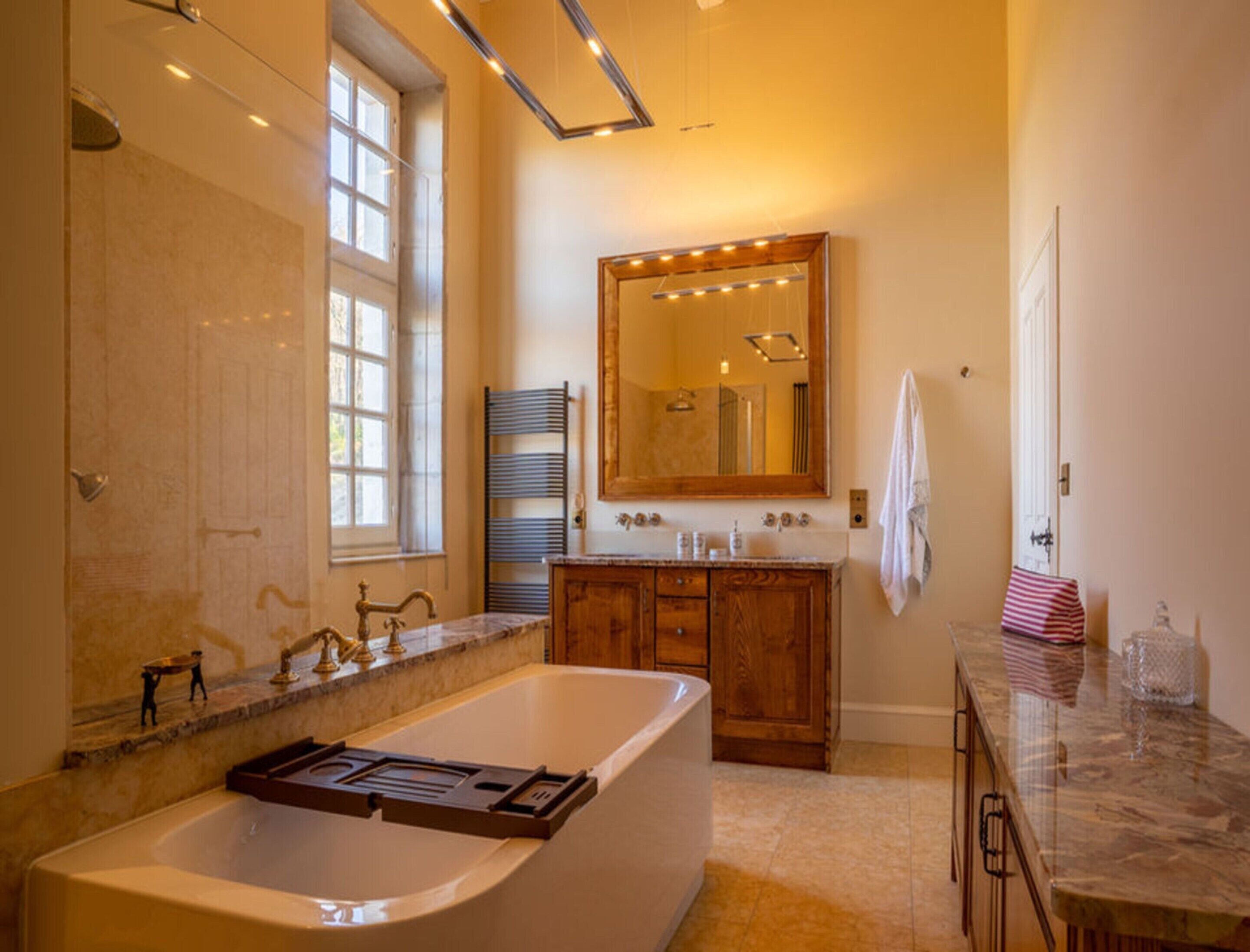 A bathroom with a large bathtub, wooden cabinets, a vanity with a mirror, and a towel rack.