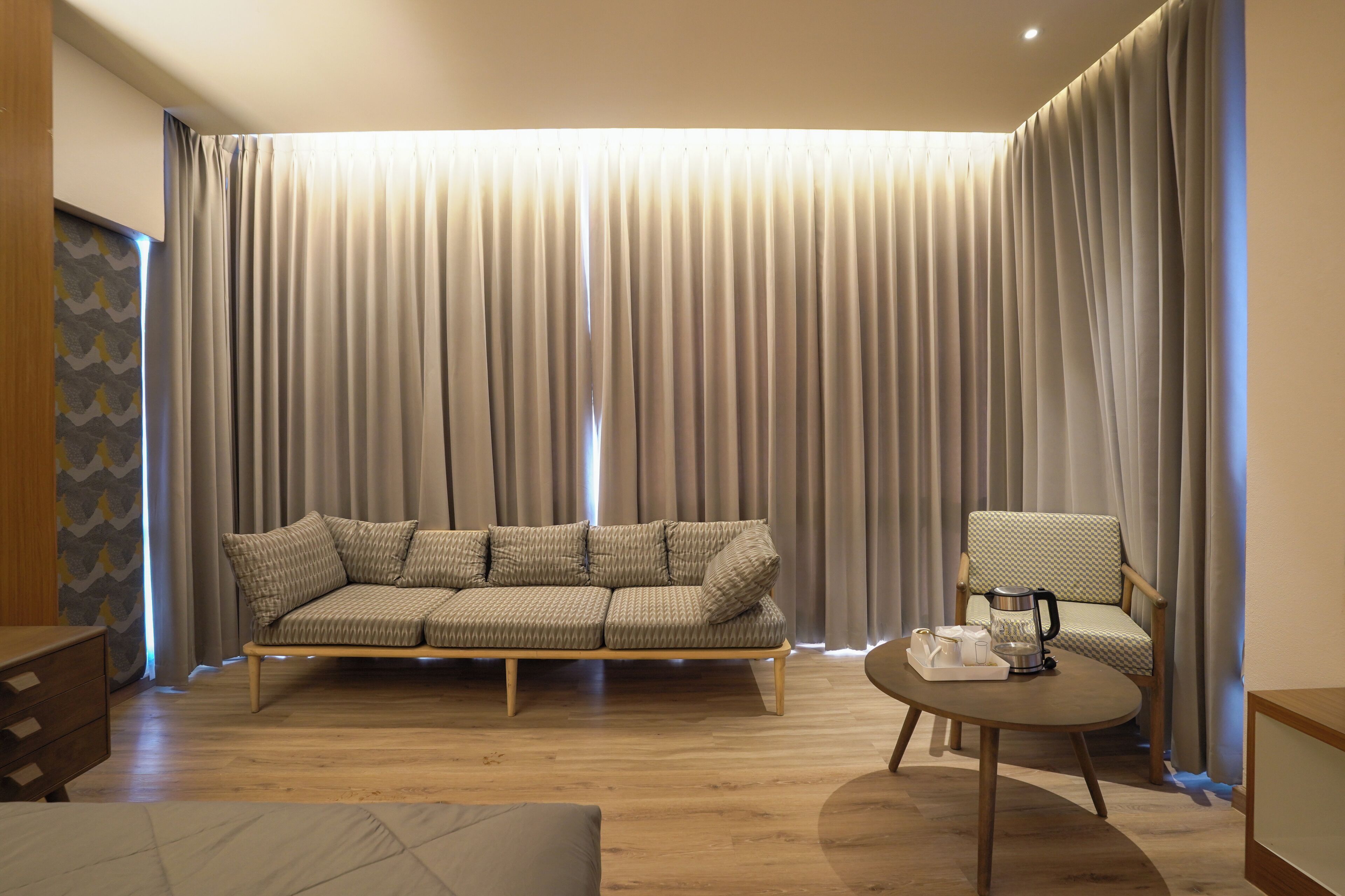 A modern living room with a sofa, a chair, a coffee table, and a large window with curtains.