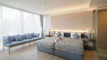 Quarto moderno com uma cama grande, um sofá e um box de vidro.