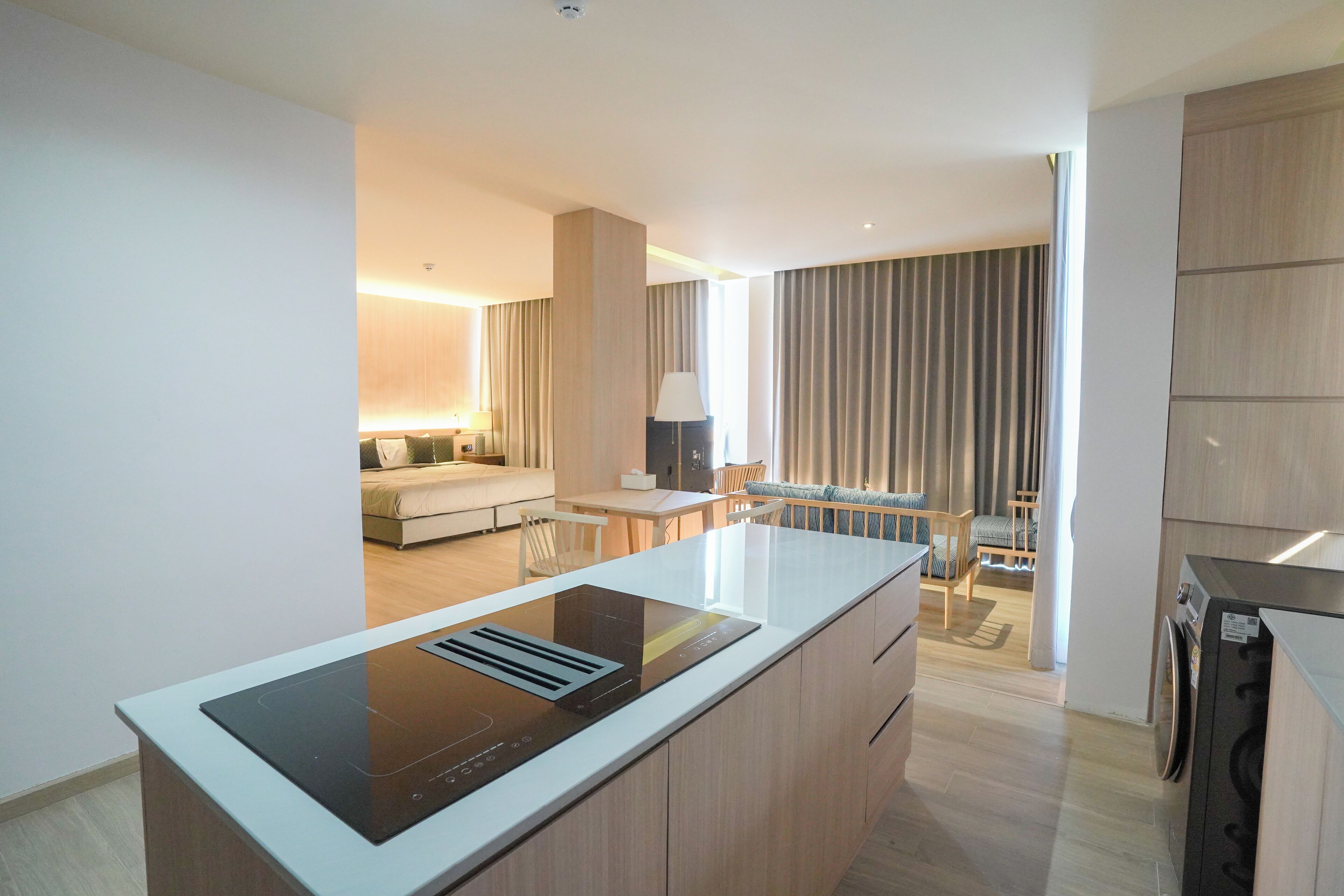 A modern kitchen with a built-in stove, a dining area with a table and chairs, and a living space with a sofa and a TV.