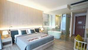 Une chambre d’hôtel moderne avec un grand lit, des tables de chevet avec des lampes, une douche en verre et une porte en bois.