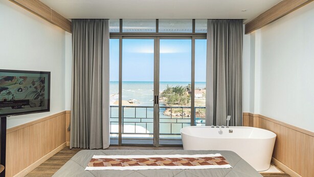 Une chambre d’hôtel avec un grand lit, une baignoire et une vue sur l’océan.