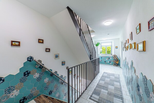A staircase with a metal railing, tiled walls, and framed pictures.