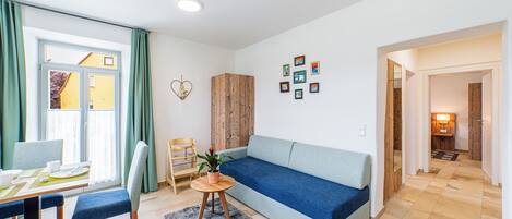 A modern living room with a sofa, chairs, a dining table, and a small table with a plant.