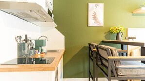A modern kitchen with a wooden countertop, a built-in stove, and a sink. There is a dining area with a table and chairs. - be Apart Hotel Serviced Apartments (Hannover)