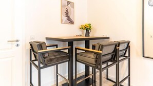 A dining area with a table and four chairs, a vase with flowers, and a framed artwork on the wall. - be Apart Hotel Serviced Apartments (Hannover)