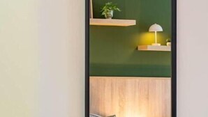 A modern room with a large mirror, a chair, and a bed with a headboard. - be Apart Hotel Serviced Apartments (Hannover)