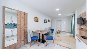 A modern kitchen with a wooden cabinet, a dining table with chairs, and a TV mounted on the wall.
