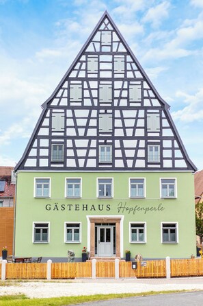 A traditional half-timbered building with a green facade and a sign reading 'GASTEHAUS Hopfenperle.' - Apartment with terrace "Zauberhopfen" (Spalt)