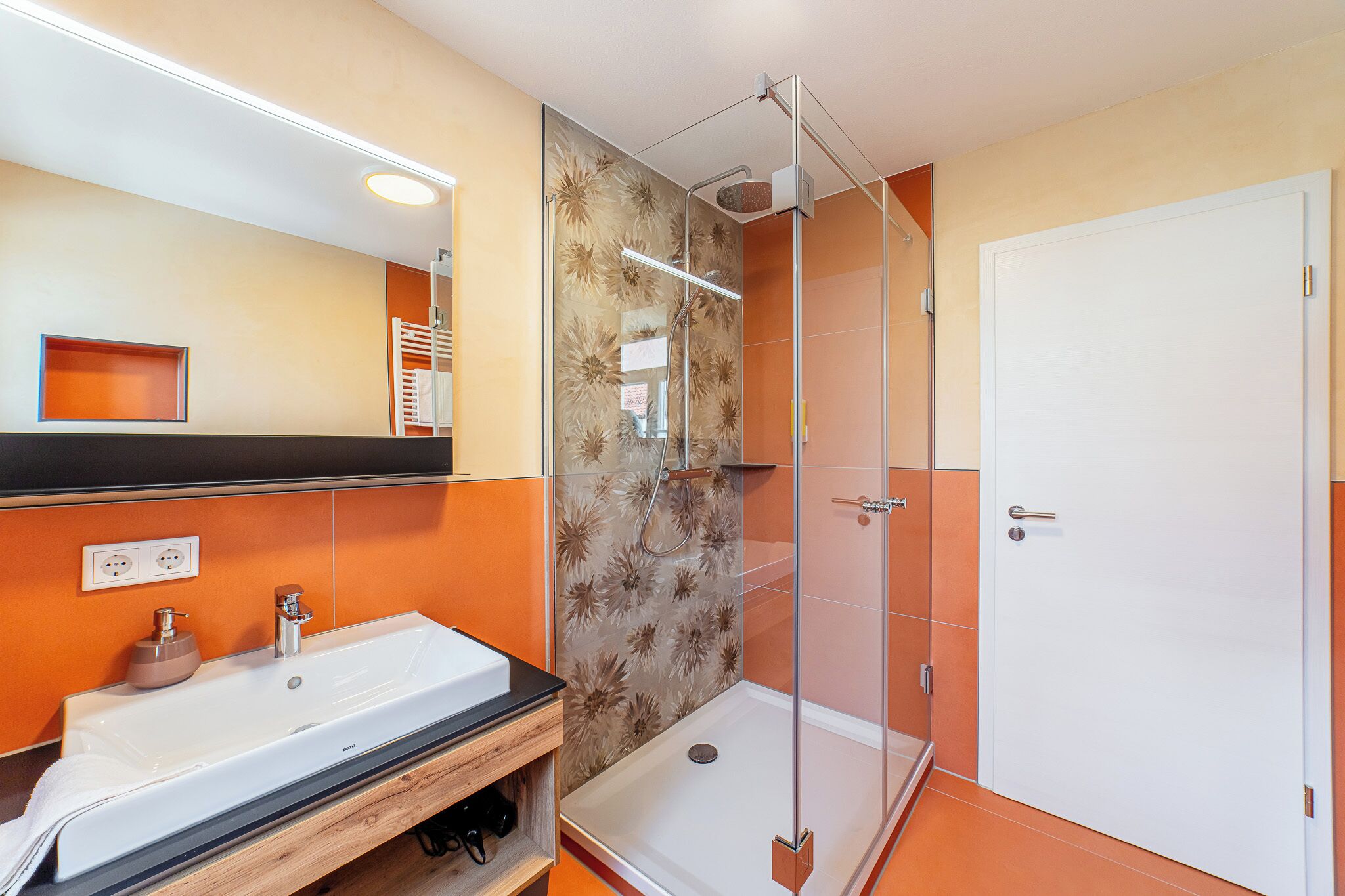 Baño con ducha, lavamanos y espejo.