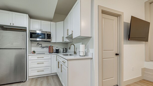 A compact kitchen with white cabinets, a stainless steel refrigerator, a microwave, and a coffee maker. - 5 Mi to Dtwn Tampa + Riverwalk: Couple's Getaway (Tampa)