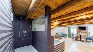 Casa de banho moderna com chuveiro, banheira e teto de madeira.