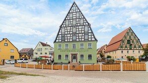 Um edifício tradicional em estilo de enxaimel com uma placa indicando 'GÄSTEHAUS Hopferperle'.