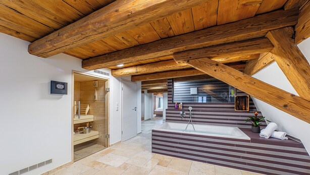 Uma casa de banho espaçosa com uma banheira grande, vigas de madeira e um design moderno.
