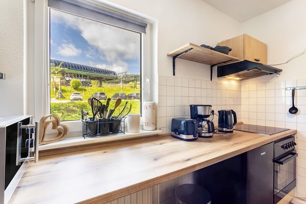 Een keuken met uitzicht door het raam, een koffiezetapparaat, een broodrooster en een waterkoker.