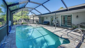 A swimming pool with a glass enclosure, a patio area with outdoor furniture, and a door with green trim. - 3 Mi to Sun Splash Waterpark! Family Haven w/ Pool (Cape Coral)