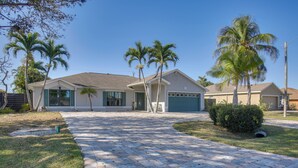 A residential house with a paved driveway, palm trees, and a well-maintained lawn. - 3 Mi to Sun Splash Waterpark! Family Haven w/ Pool (Cape Coral)