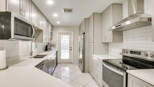 A modern kitchen with stainless steel appliances, white cabinetry, and a tiled floor. - 3 Mi to Sun Splash Waterpark! Family Haven w/ Pool (Cape Coral)