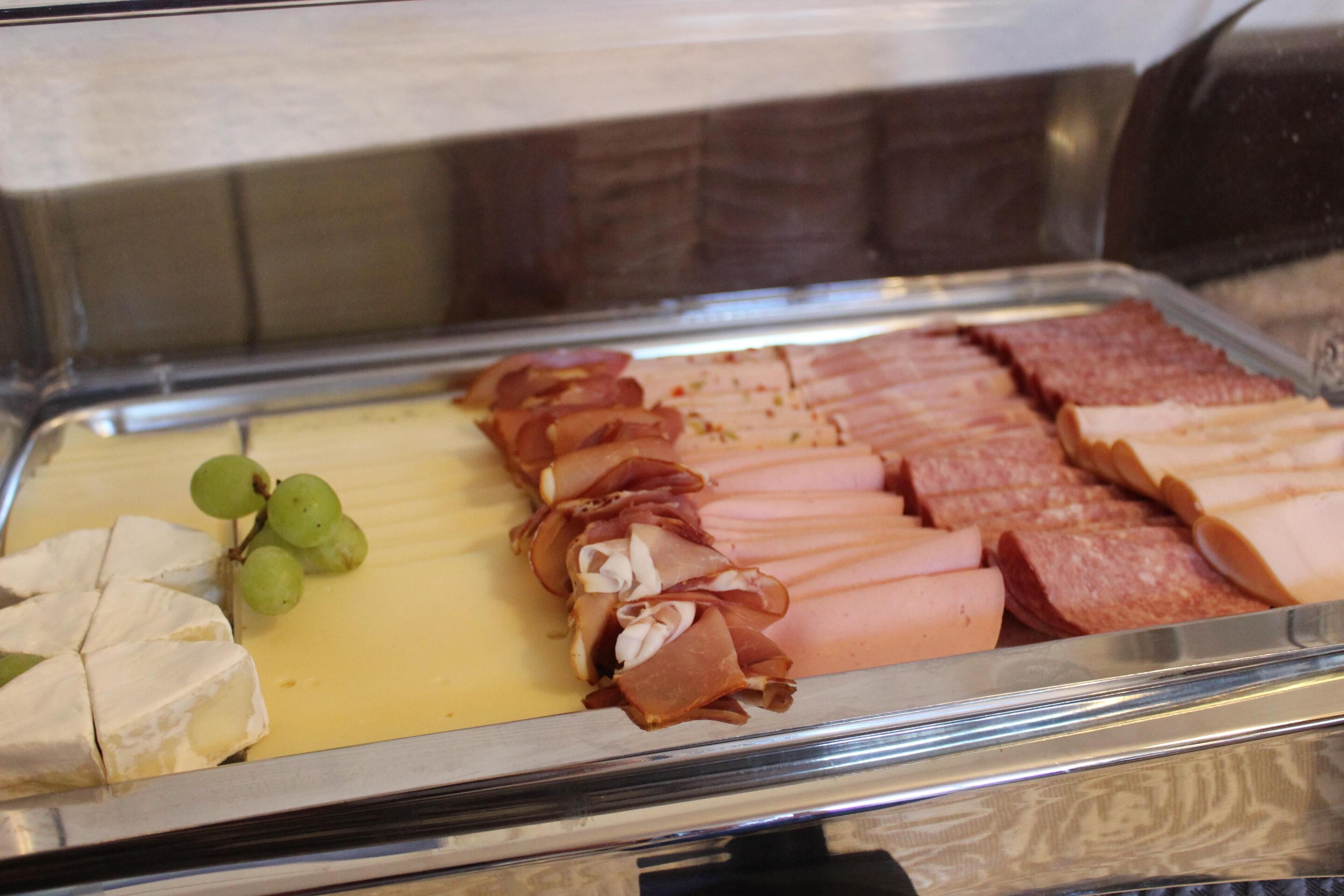 A buffet with various meats and cheese.