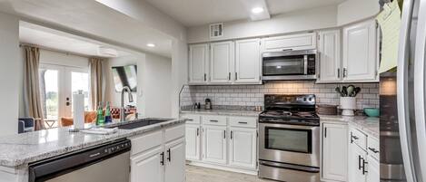 A modern kitchen with white cabinets, stainless steel appliances, and a dishwasher.
