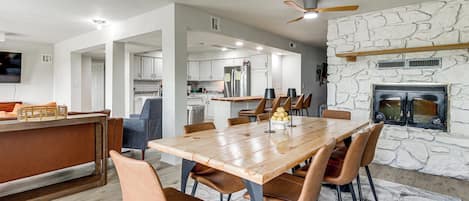 Une cuisine moderne avec un mur en pierre, un coin repas avec une table et des chaises en bois, et une cheminée intégrée.