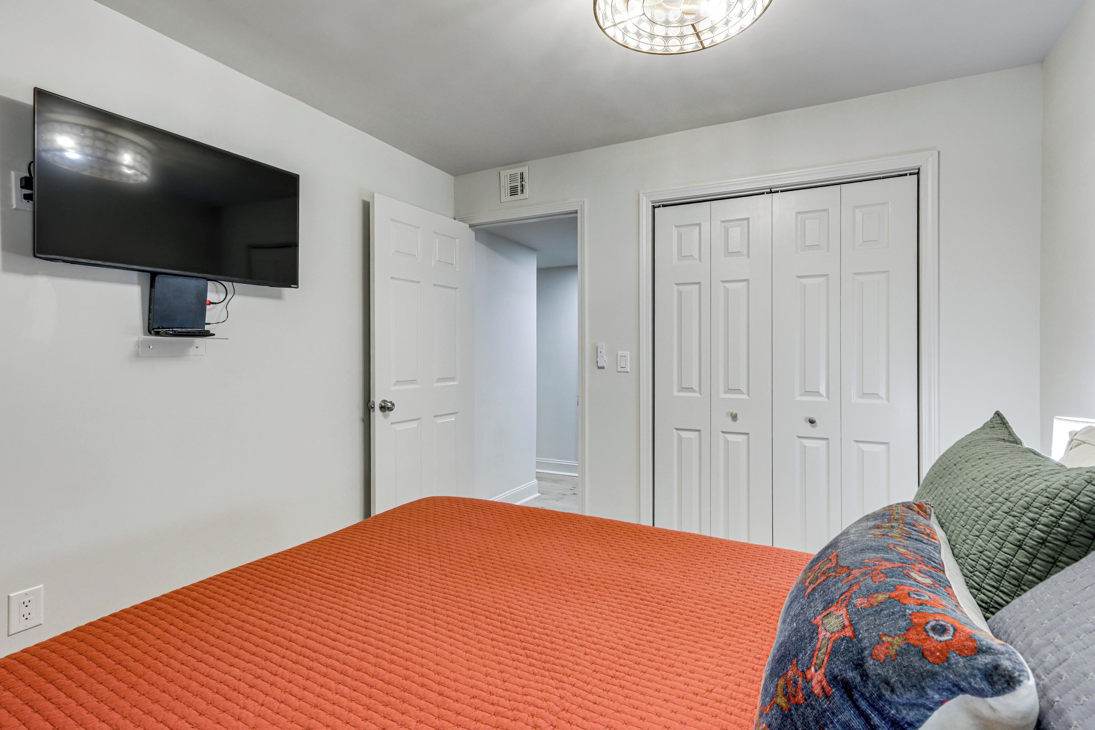 A bedroom with a bed, a television mounted on the wall, and a door leading to another room.