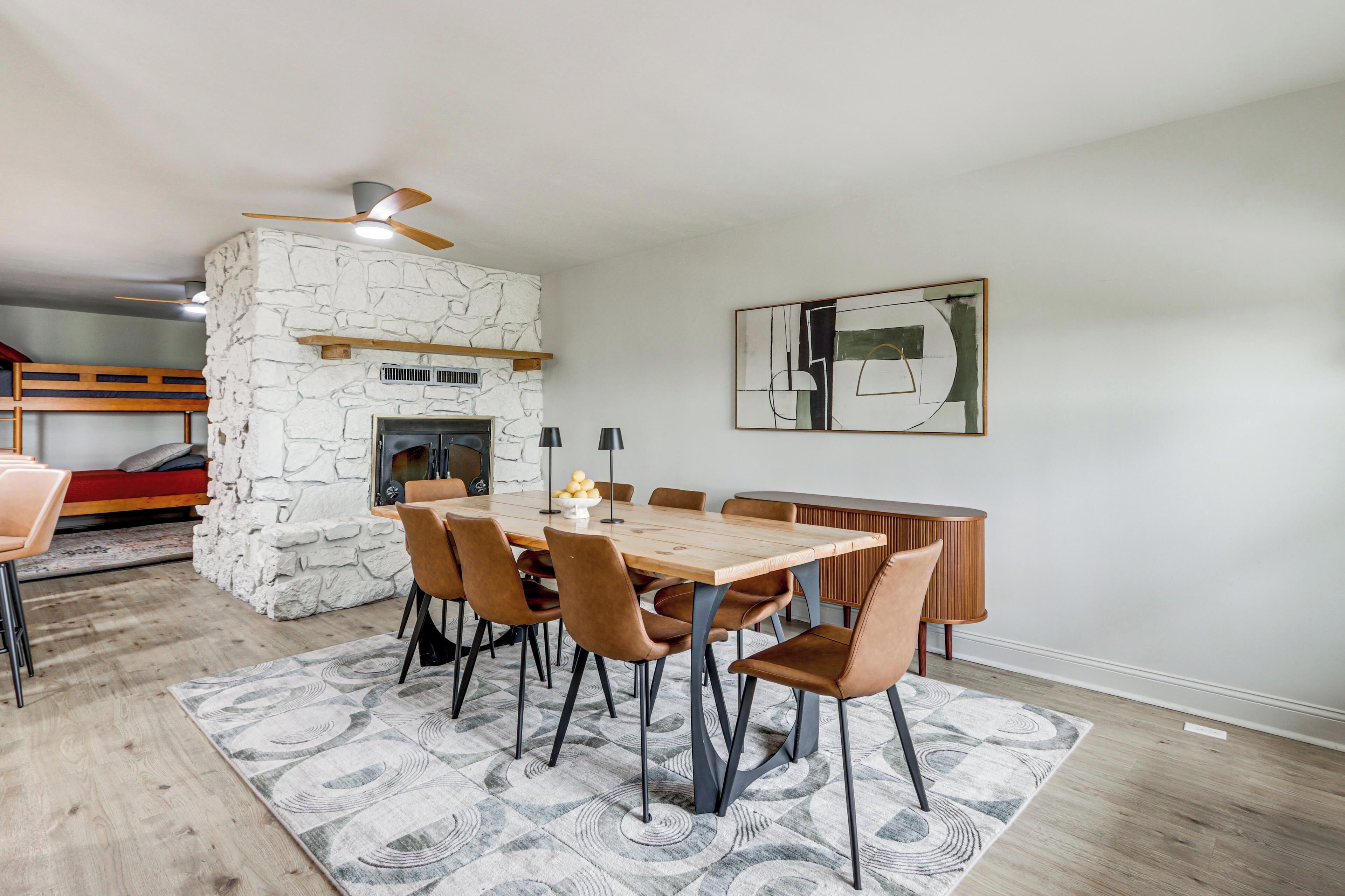 A dining area with a stone fireplace, a wooden table, and chairs.