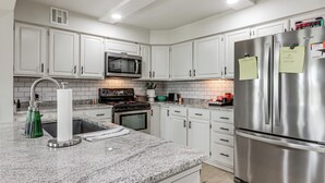 A modern kitchen with white cabinets, stainless steel appliances, and a granite countertop. - Patio + Golf Course Views: Monkey Island Escape! (Afton)