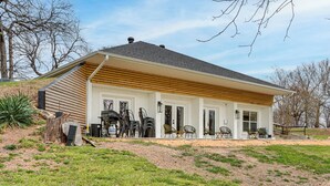 A single-story house with a sloped roof, a covered porch with outdoor seating, and a small front yard. - Patio + Golf Course Views: Monkey Island Escape! (Afton)