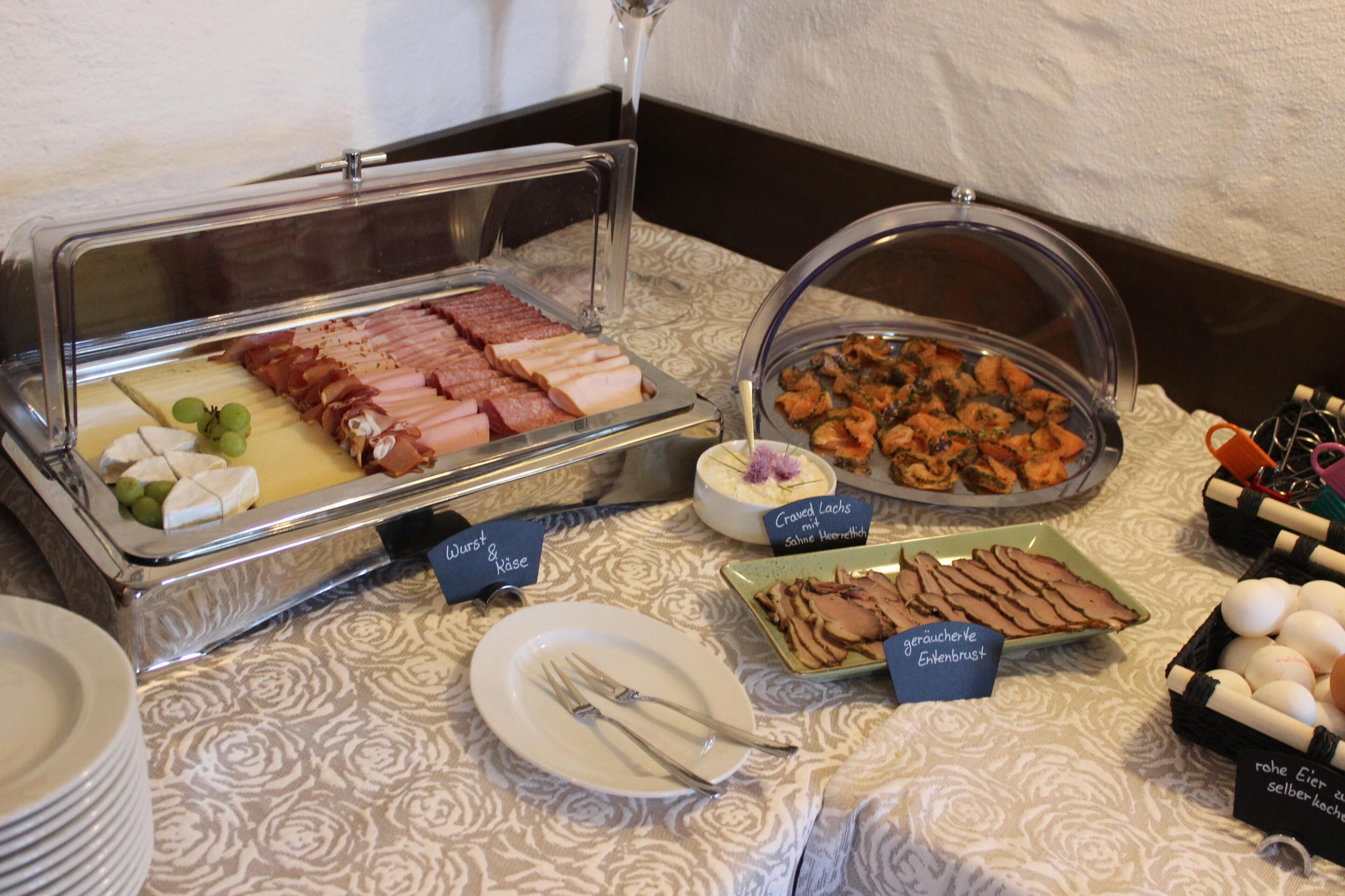 Un buffet proposant une variété de plats, notamment des viandes, des fromages et des fruits.