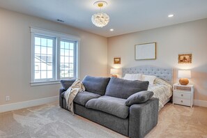 A bedroom with a bed, a grey sofa, a nightstand, a lamp, and a window. - 'bearly Behaven' Near Bear Lake & Marina! (Garden City)