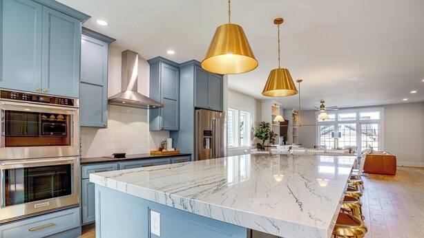 A modern kitchen with blue cabinets, stainless steel appliances, a marble island, and gold pendant lights. - 'bearly Behaven' Near Bear Lake & Marina! (Garden City)