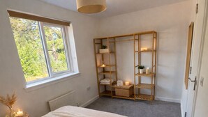 Ein Schlafzimmer mit einem großen Bett, einem Fenster, einer Holzregalanlage und einer Deckenleuchte.