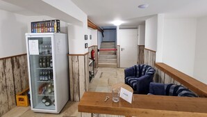A hotel lobby with a reception desk, a refrigerator stocked with beverages, a staircase, and a fire extinguisher.