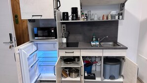A compact kitchen with a Bosch microwave, a sink, and a refrigerator with a glass door.