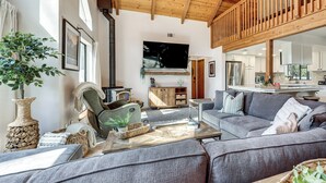 Una sala de estar con sofá, una butaca, televisor y chimenea.