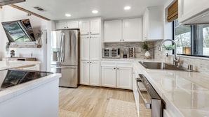 Una cocina moderna con armarios blancos, electrodomésticos de acero inoxidable y una isla grande.