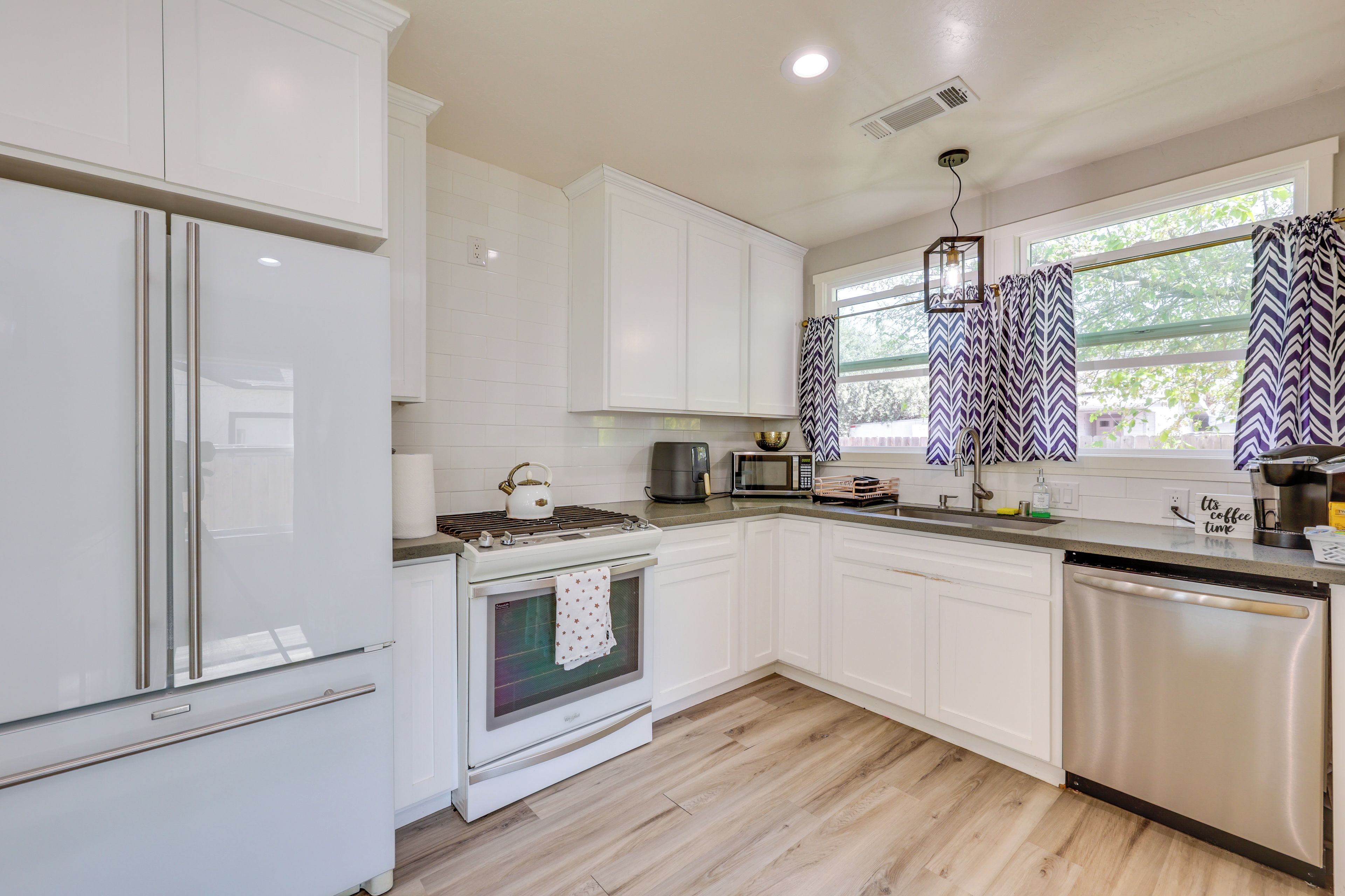 Una cocina moderna con armarios blancos, electrodomésticos de acero inoxidable y piso de madera.