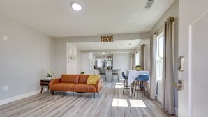A spacious living area with a brown leather sofa, a dining table with chairs, and a kitchen in the background. - < 1 Mi to Main St Hanford! Home w/ Outdoor Space (Hanford)
