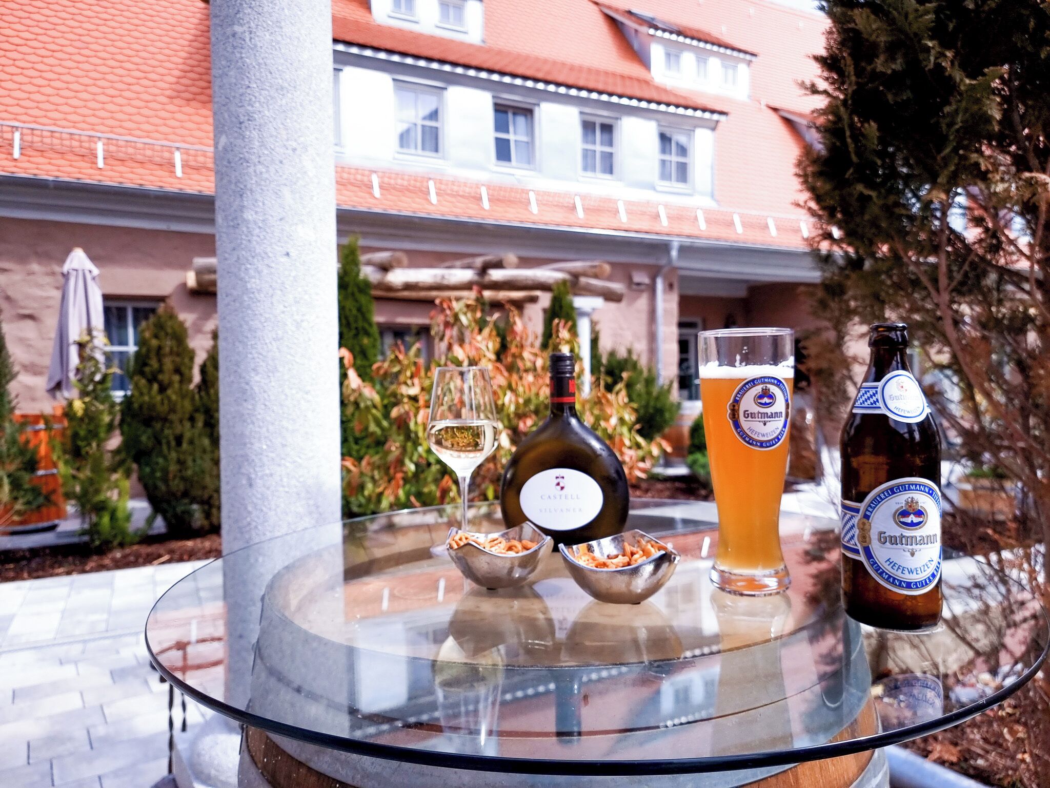 Ein Glastisch mit einer Flasche Castello Silvano Wein, einem Bierglas und zwei Schalen mit Snacks.