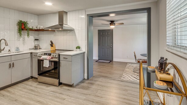 A modern kitchen with white cabinets, stainless steel appliances, and a wooden floor. - Pensacola Retreat: Near Fall Festivals & Events (Gulf Breeze)