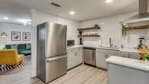 A modern kitchen with stainless steel appliances, white cabinetry, and a wooden floor. - Pensacola Retreat: Near Fall Festivals & Events (Gulf Breeze)