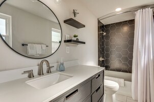 Un baño moderno con un espejo grande, un lavabo, un inodoro y una zona de ducha.