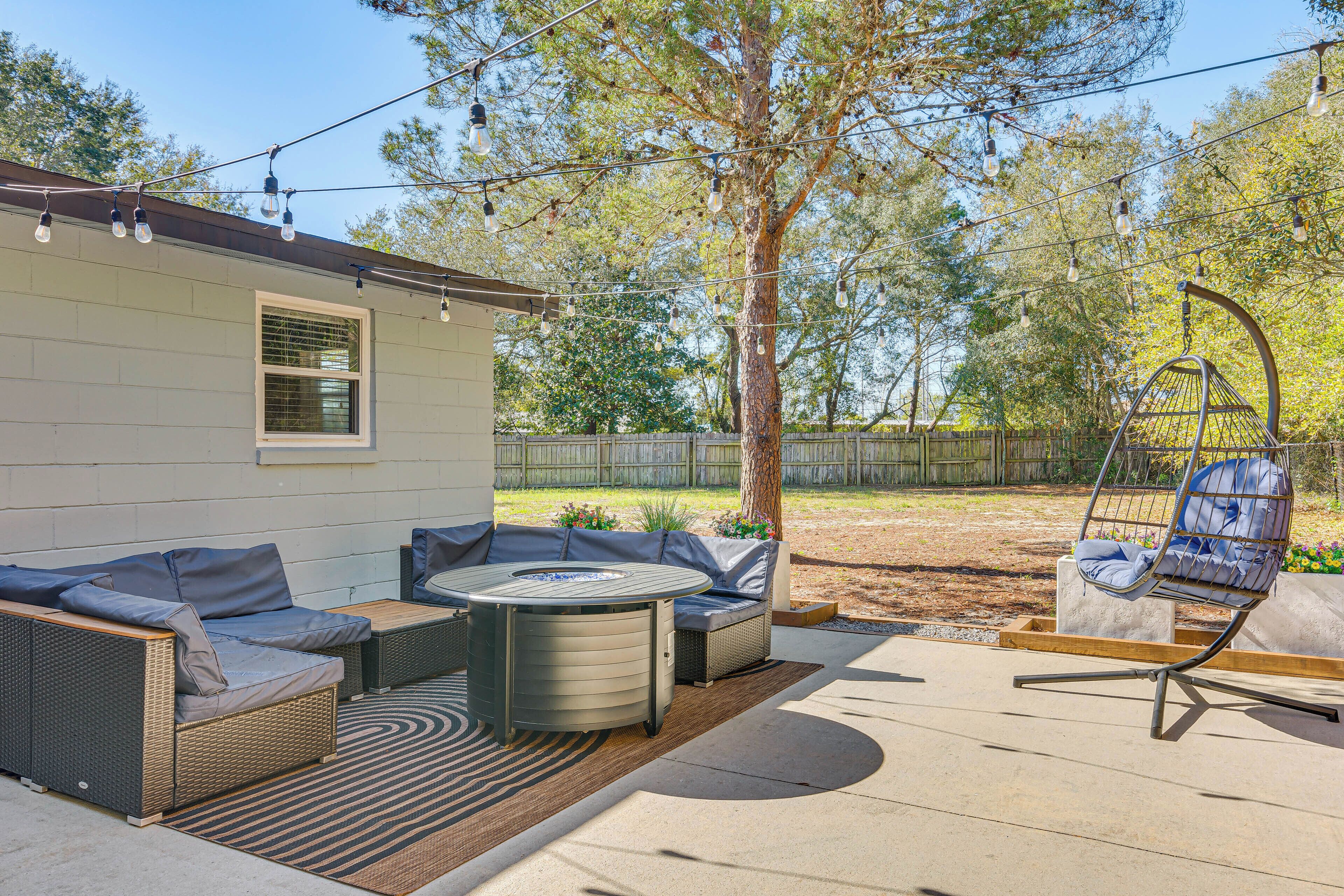 An outdoor patio with a sofa set, a round table, and a hanging chair.