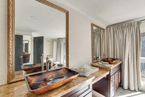 A bathroom with a large mirror, a unique vessel sink, and a view of the outdoors.