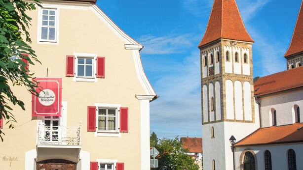 Ein Gebäude mit einem roten Kreuz auf dem Dach, einem Balkon und einem Schild mit einem Logo.