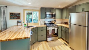 A kitchen with a wooden countertop, stainless steel appliances, and green cabinets. - 1 Mi to Woodland Lake! Cabin w/ Dog-friendly Yard (Pinetop)