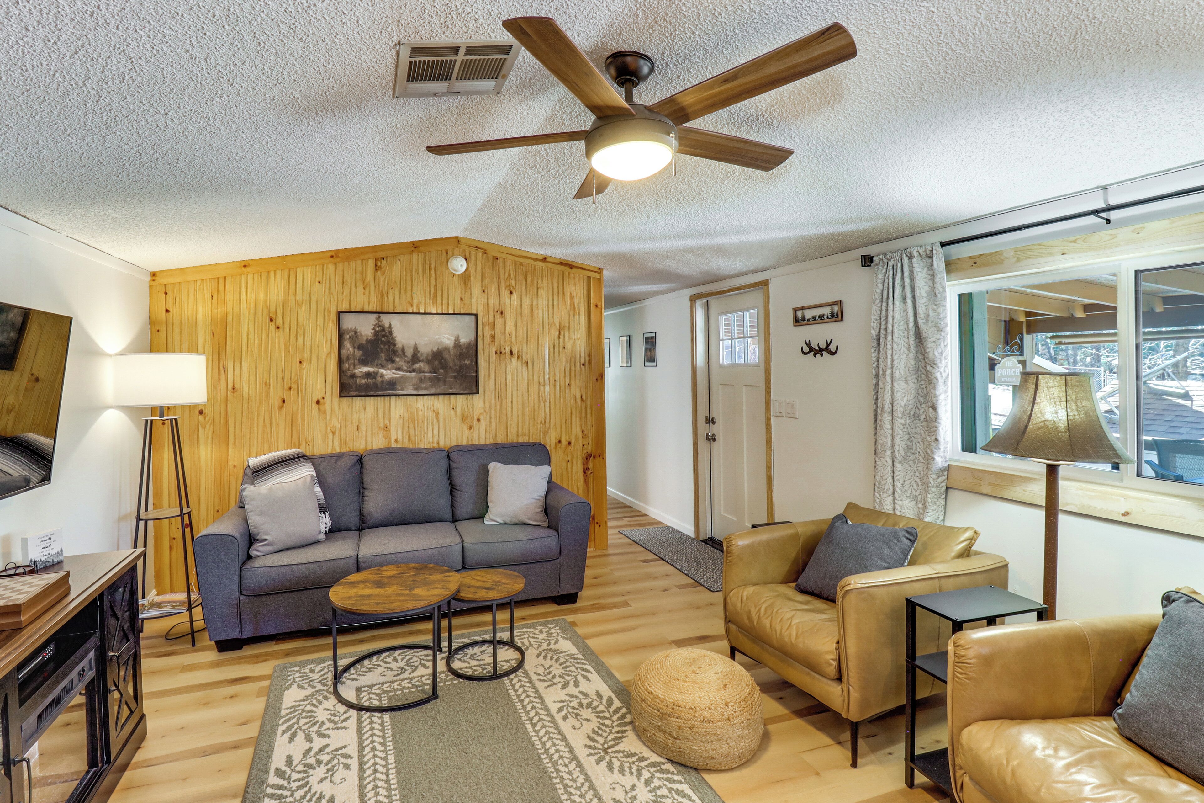 A living room with a sofa, armchair, coffee table, and a ceiling fan.