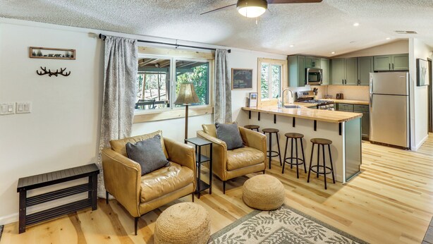 A modern kitchen with a central island, bar stools, and a ceiling fan. - 1 Mi to Woodland Lake! Cabin w/ Dog-friendly Yard (Pinetop)