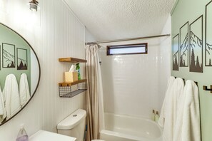 A bathroom with a bathtub, toilet, and a mirror.